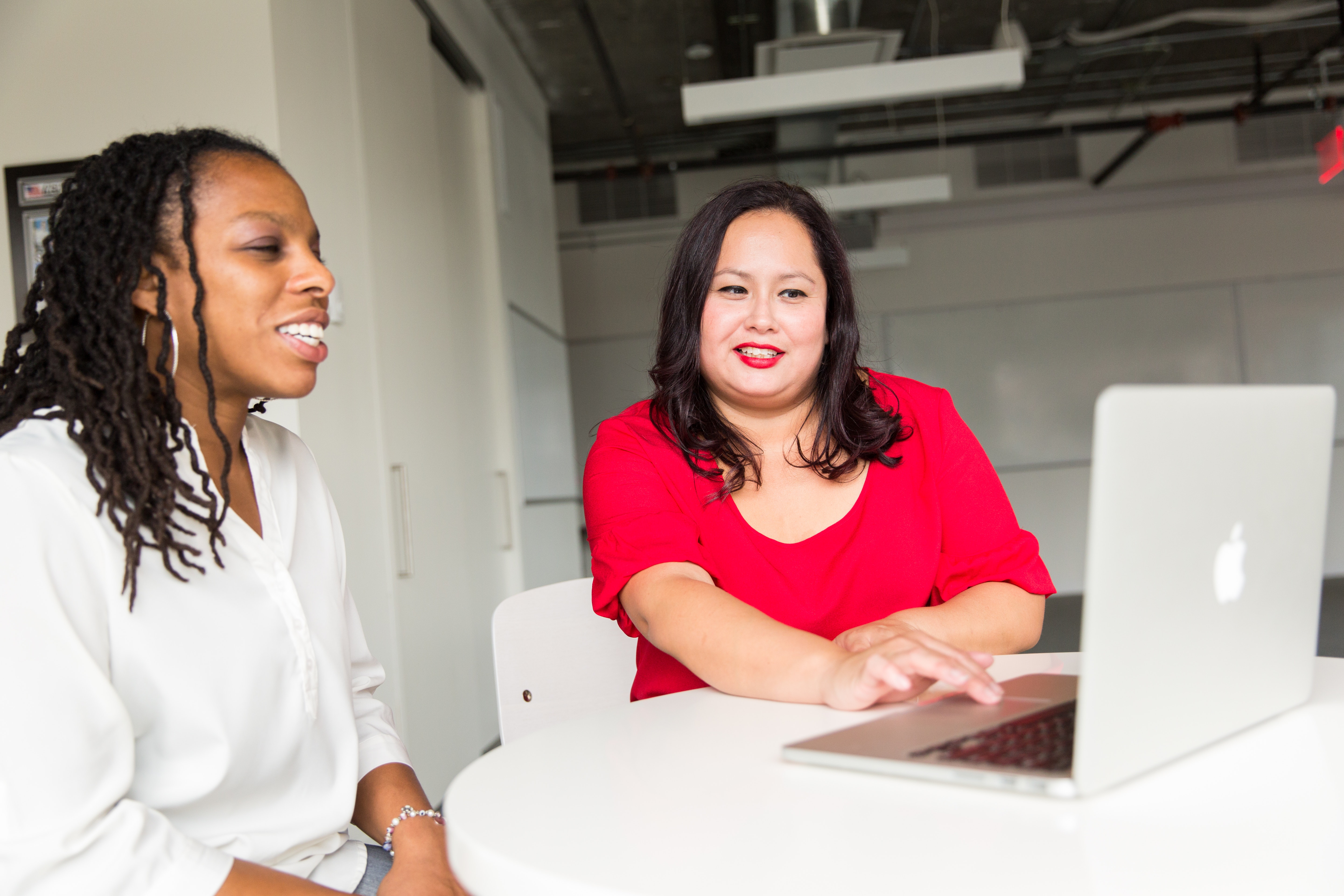 2 women sitting in front of laptop, talking