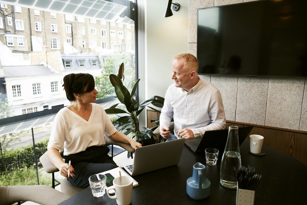 man and woman sitting at desk, with laptops